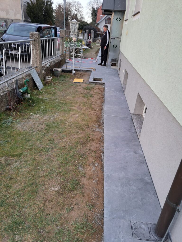 Vorbereitung des Untergrunds für Außenfliesen entlang einer Hausfassade in Niederösterreich